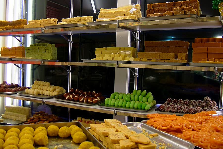 A sweet shop shelf stacked with colourful Indian sweets for Diwali