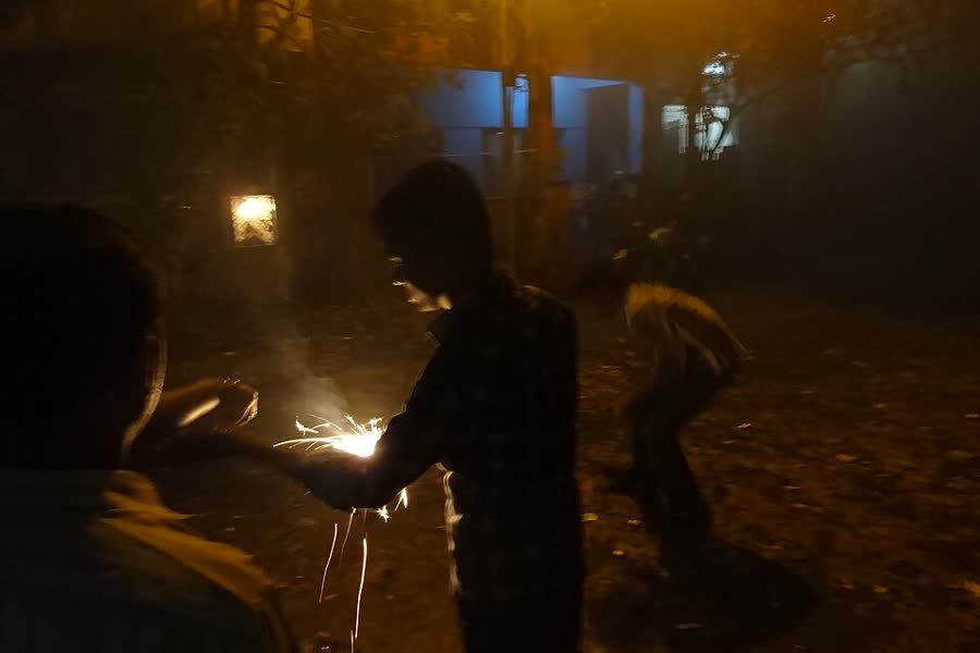 Children lighting firecrackers on a dark street during Deepavali