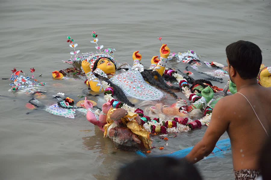 A man guides a Durga idol into the River Hooghly at Baghbazar Ghat during immersion