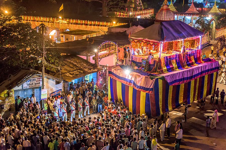 A tall decorated wooden chariot lit up at night during Bastar Dussehra in Jagdalpur