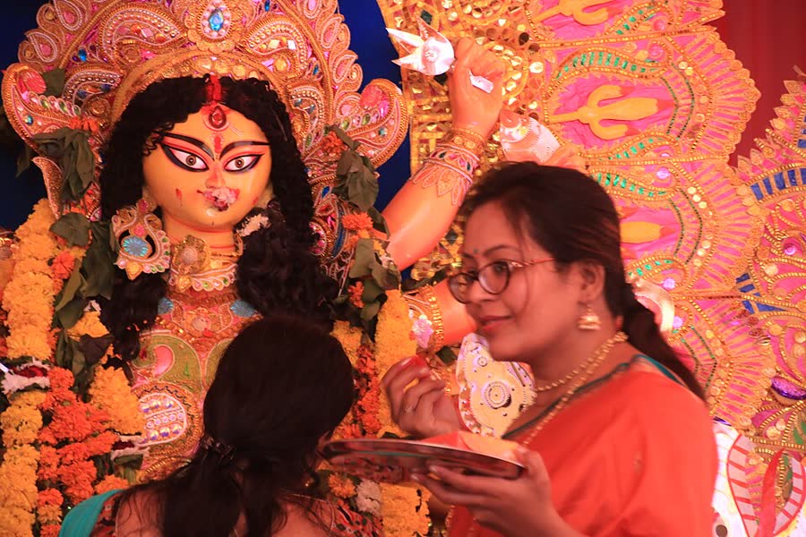A woman offering sindoor to the goddess Durga at a puja pandal